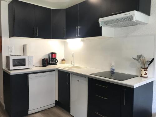 - une cuisine avec des armoires noires et un four micro-ondes blanc dans l'établissement Pied télécabine avec parking couvert, T2 bis 5 personnes., à Cauterets