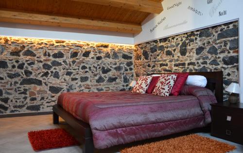 una camera da letto con divano e parete in pietra di Casa Alcalà Deluxe a Catania