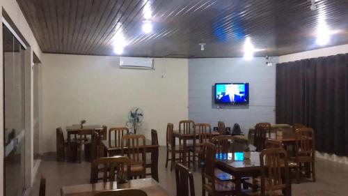 a room with tables and chairs and a tv on a wall at Hotel Solar Flores in Alegrete