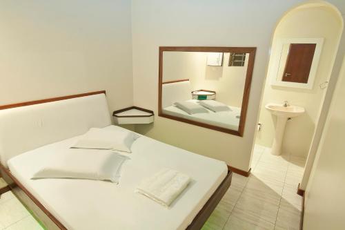 a bedroom with a white bed and a mirror at MOTEL 3 PEIXINHOS (Adults Only) in Blumenau
