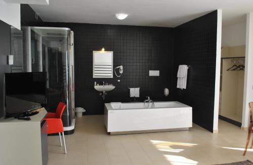 ein Badezimmer mit einer weißen Badewanne und einem Waschbecken in der Unterkunft Althea Palace Hotel in Castelvetrano Selinunte