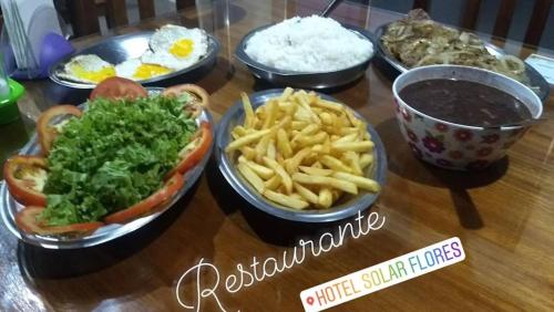a table topped with bowls of food and french fries at Hotel Solar Flores in Alegrete