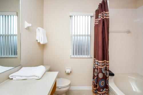 La salle de bains est pourvue de toilettes, d'un lavabo et d'une baignoire. dans l'établissement Loyalty Vacation Homes - Kissimmee, à Orlando