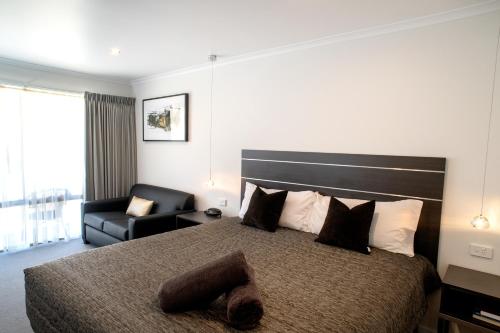 um quarto de hotel com uma cama e uma cadeira em Tea House Motor Inn em Bendigo