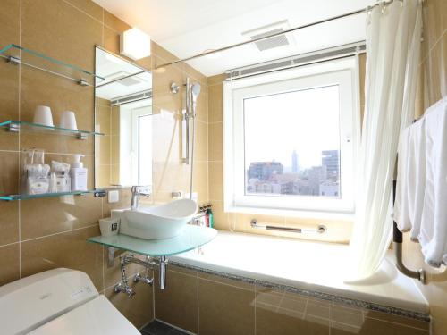 La salle de bains est pourvue d'un lavabo et d'une fenêtre. dans l'établissement APA Hotel Asakusa Kaminarimon, à Tokyo