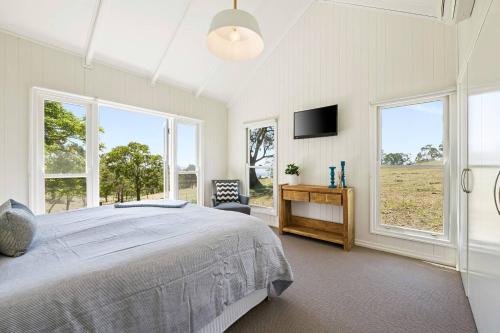 Schlafzimmer mit einem Bett, einem Schreibtisch und Fenstern in der Unterkunft Hollow Tree Farm in Toowoomba