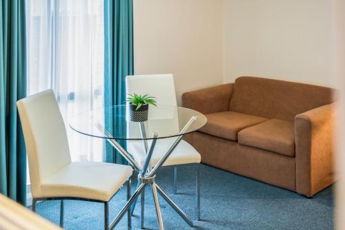 a living room with a glass table and a couch at Garden City Motor Inn in Wagga Wagga