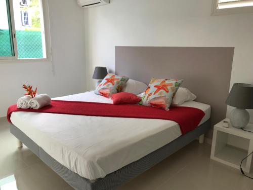 ein Schlafzimmer mit einem Bett mit einer roten Decke und Kissen in der Unterkunft EVASION CARAÏBES in Roussel