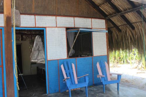 two blue chairs sitting outside of a building at Eco Hotel Las Palmeras in Isla Grande