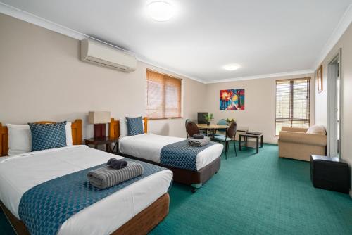 a hotel room with two beds and a desk at Garden City Motor Inn in Wagga Wagga