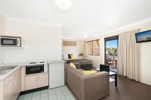 a kitchen with a refrigerator, stove, microwave and a sink at Byron Bayside Central Studio Apartments in Byron Bay