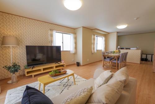 a living room with a couch and a flat screen tv at Hyakuna Terrace in Nanjo