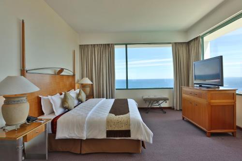 a hotel room with a bed and a flat screen tv at Aryaduta Manado in Manado