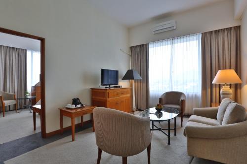 a living room with a room with a couch and a tv at Aryaduta Manado in Manado