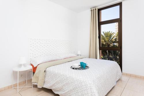 a white bedroom with a bed with a tray on it at Las Américas Downtown : Prime location accomm. in Arona
