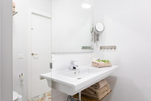 uma casa de banho branca com um lavatório e um espelho em Las Américas Downtown : Prime location accomm. em Arona