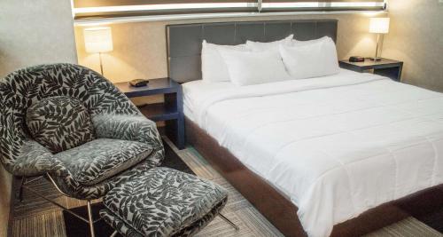 a bed and a chair in a hotel room at The Rushmore Hotel & Suites; BW Premier Collection in Rapid City