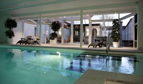 a swimming pool in a house with chairs and plants at Golf Hotel Viborg in Viborg