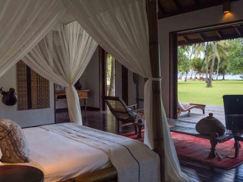 una camera con letto a baldacchino e patio di Sira Beach House a Tanjung