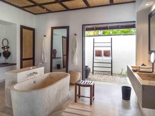 un ampio bagno con grande vasca e lavandino di Sira Beach House a Tanjung