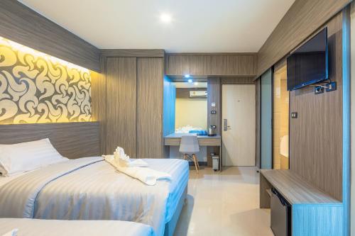 a hotel room with two beds and a television at Sound@sleep Hotel in Bangkok