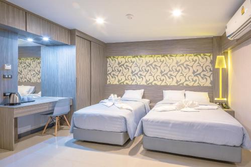 a bedroom with two beds and a desk and a sink at Sound@sleep Hotel in Bangkok
