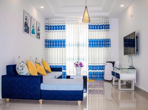 a living room with a blue couch and yellow pillows at Căn hộ Nghỉ Dưỡng Aparment Melody Vũng Tàu - Tomorrow Homestay 1 in Vung Tau
