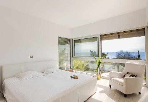 a white bedroom with a white bed and a chair at Katerina House in Perivolia