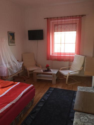 a bedroom with a bed and chairs and a window at Tó Panzió Őrség Bajànsenye in Bajánsenye