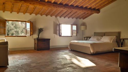 a bedroom with a bed and a table and windows at Agriturismo Villa Gorgognano in Certaldo