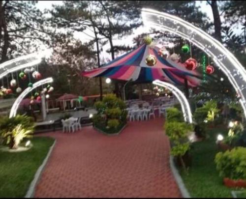 a garden with an umbrella and tables and chairs at M&M Residence in Baguio
