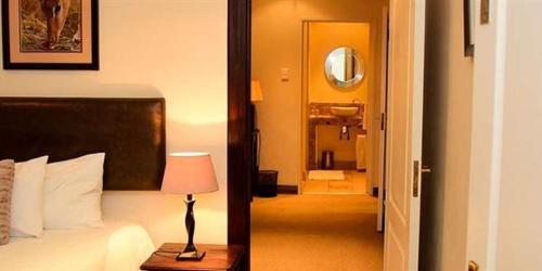 a bedroom with a bed and a lamp on a table at Kalahari Lodge Kimberley in Kimberley