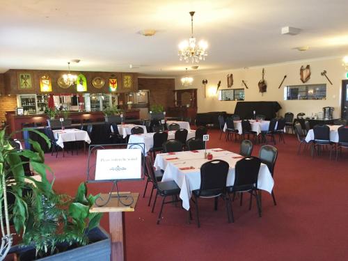 ein Esszimmer mit weißen Tischen und Stühlen in der Unterkunft Castle Motor Lodge in Bowen