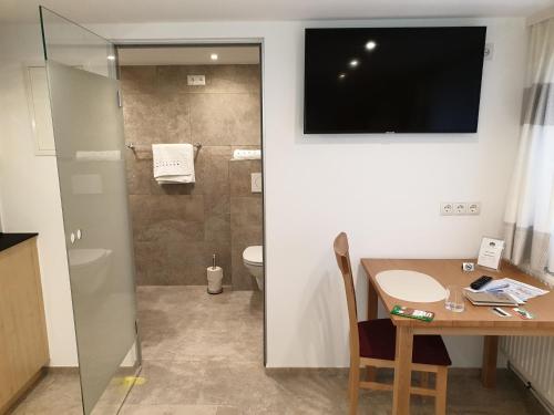 a bathroom with a shower and a table and a television at Ferienwohnung Metzler - Blick auf die Berge in Göfis