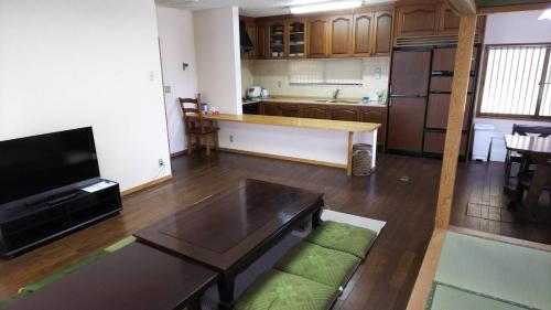 a living room with a table and a kitchen at 森と空と家 Spacious private house Moritosora in Sammu