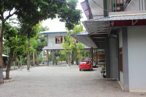 a red van parked on a street next to a building at Pondok Wisata dan Restoran Elim in Waingapu