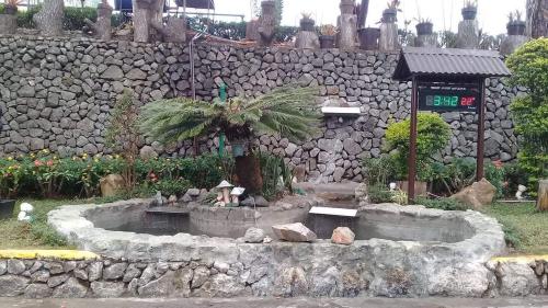a garden with a fountain in front of a stone wall at M&M Residence in Baguio