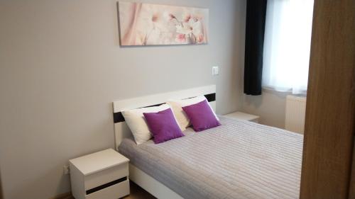Dormitorio pequeño con cama con almohadas moradas en Apartament Marzenie 6 - Opole en Opole