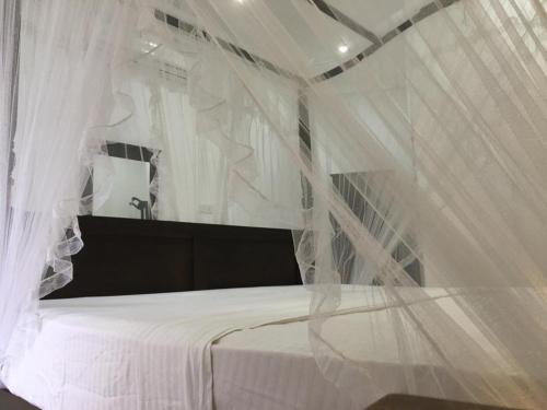 a bedroom with a bed covered in white curtains at Galle Fantacy in Unawatuna