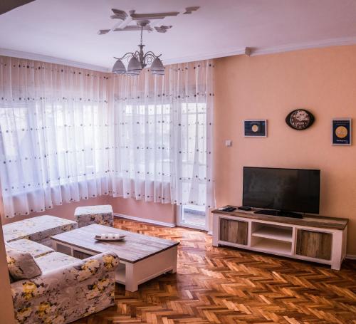 uma sala de estar com um sofá e uma televisão em Two Bedroom Apartment Downtown Ivanovi em Varna
