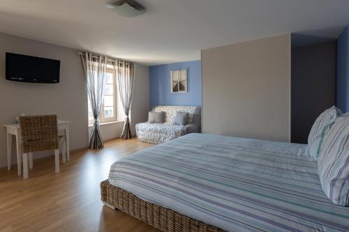 a bedroom with a bed and a chair and a couch at Les Voyageurs in Saint-Martin-la-Méanne