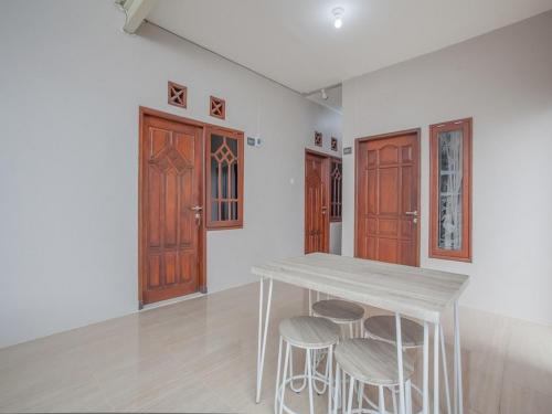 a white room with a wooden table and stools at RedDoorz near Ciputra Golf Surabaya in Surabaya