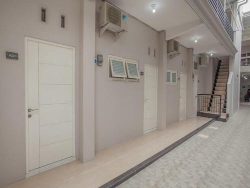 a hallway with white doors and stairs in a building at RedDoorz near Ciputra Golf Surabaya in Surabaya