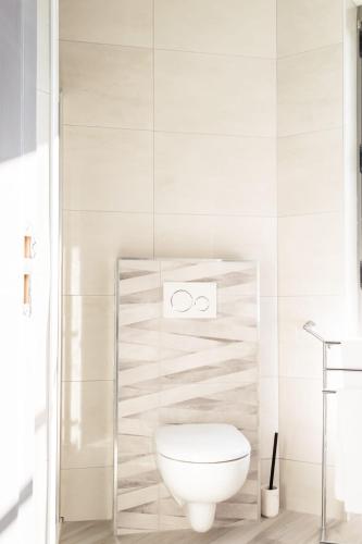 a white bathroom with a toilet in a room at Hotel des Iris in Auvers-sur-Oise