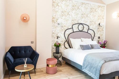a bedroom with a bed and a blue chair at Hotel des Iris in Auvers-sur-Oise