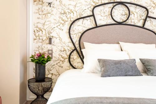 a bedroom with a white bed and a floral wallpaper at Hotel des Iris in Auvers-sur-Oise