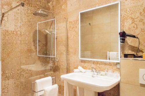 a bathroom with a sink and a shower at Hotel des Iris in Auvers-sur-Oise