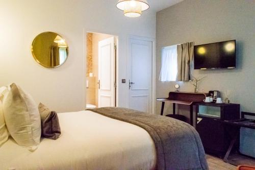 a bedroom with a bed and a table and a mirror at Hotel des Iris in Auvers-sur-Oise