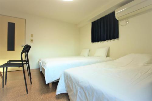 a hotel room with two beds and a chair at Kyoto Yoshii House in Kyoto