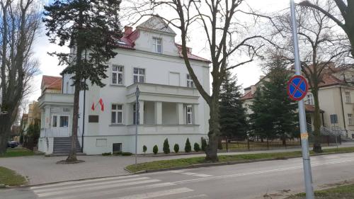 een wit gebouw op een straat met een straatbord bij Willa Ostoja in Inowrocław